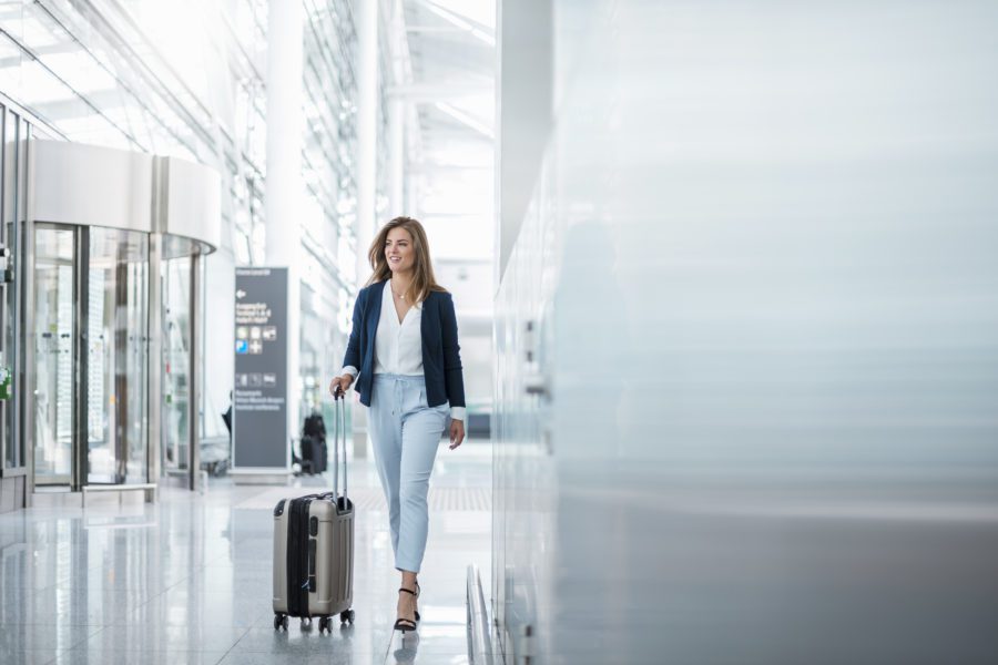 A woman in business attire walks through the airport terminal, efficiently pulling her rolling suitcase. She’s balancing work and leisure with ease, having mastered the art of tracking employee time off to enjoy well-deserved breaks without missing a beat.