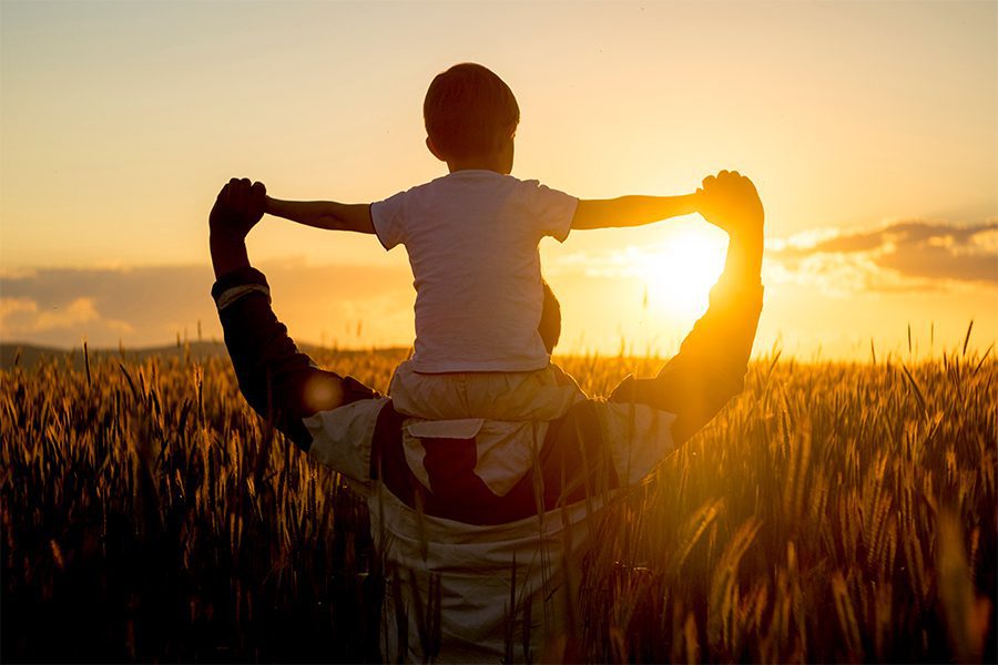 Father With Son On Shoulders Looking At Sunset