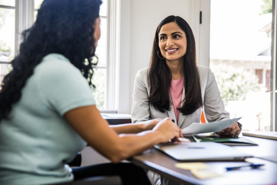 Two women in a professional setting going over documents during a discussion