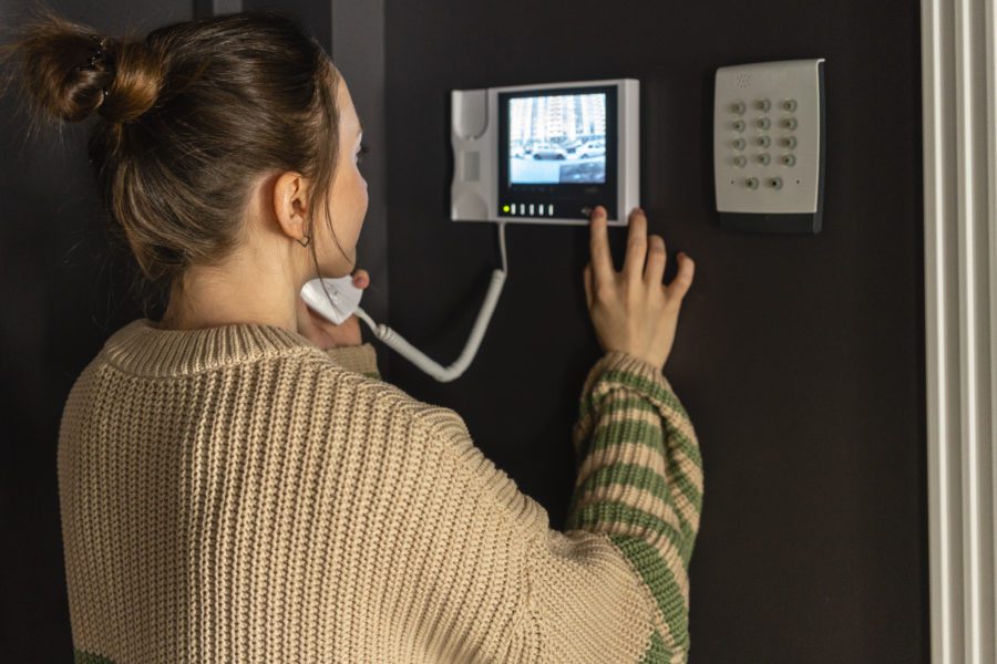 A woman using an intercom system with a video screen and keypad