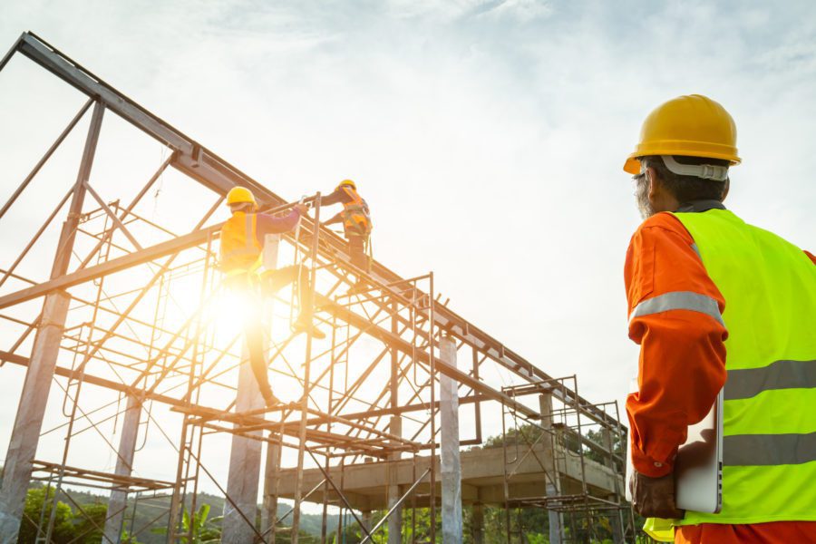 Construction workers in safety gear working together to build a metal structure