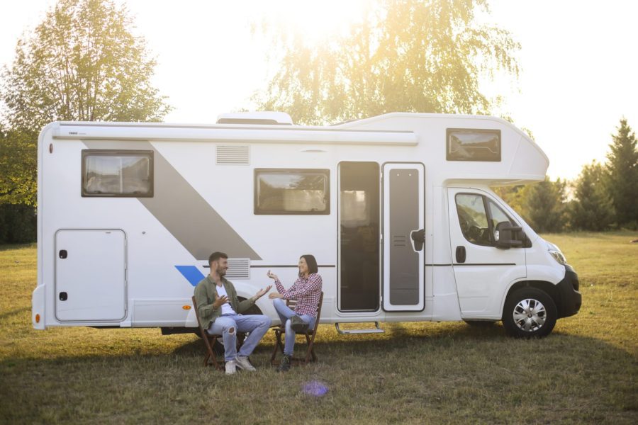 Two people sitting on chairs outside an RV chatting and enjoying each other's company