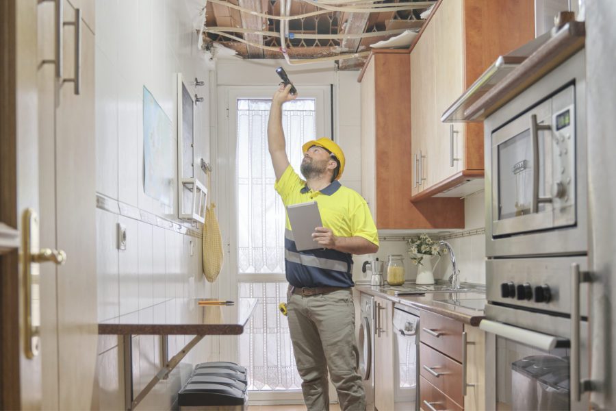 Maintenance worker checking the water damage done to the ceiling after a storm