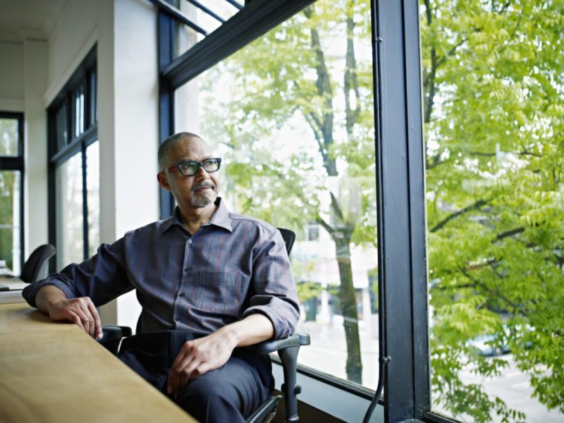 Businessman Sitting At Desk Looking Out Window