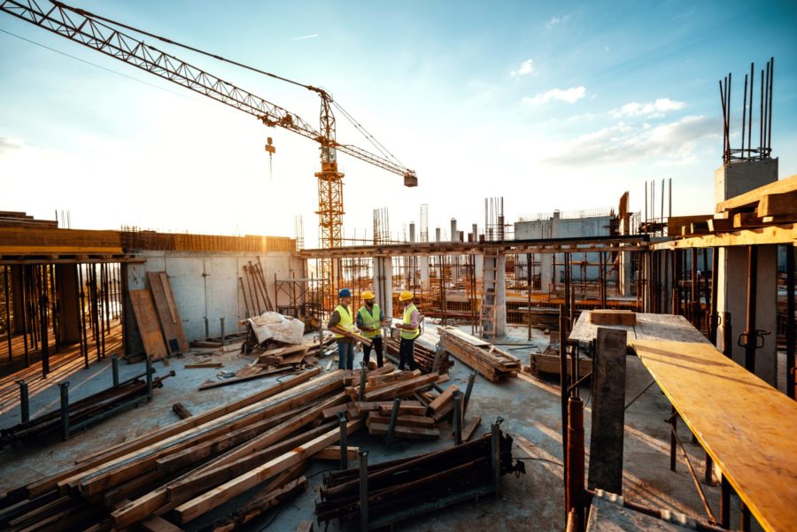 architects and engineers discussing work progress between concrete walls, scaffolds and cranes.