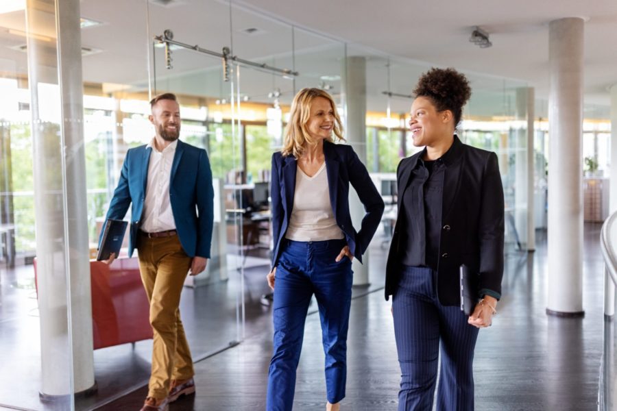 Team Of Corporate Professionals Moving Through The Office Corridor