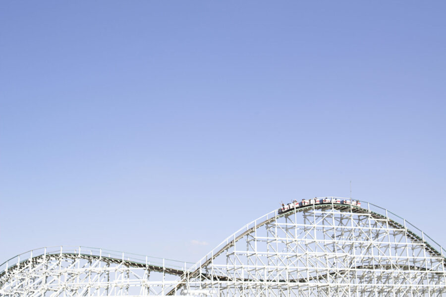 Rollercoaster With People Raising Arms In Air In Cars On Top