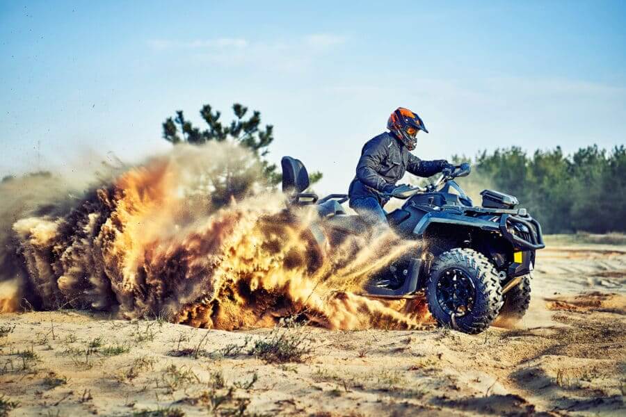 Teen Riding ATV In Sand Dunes Making A Turn In The Sand