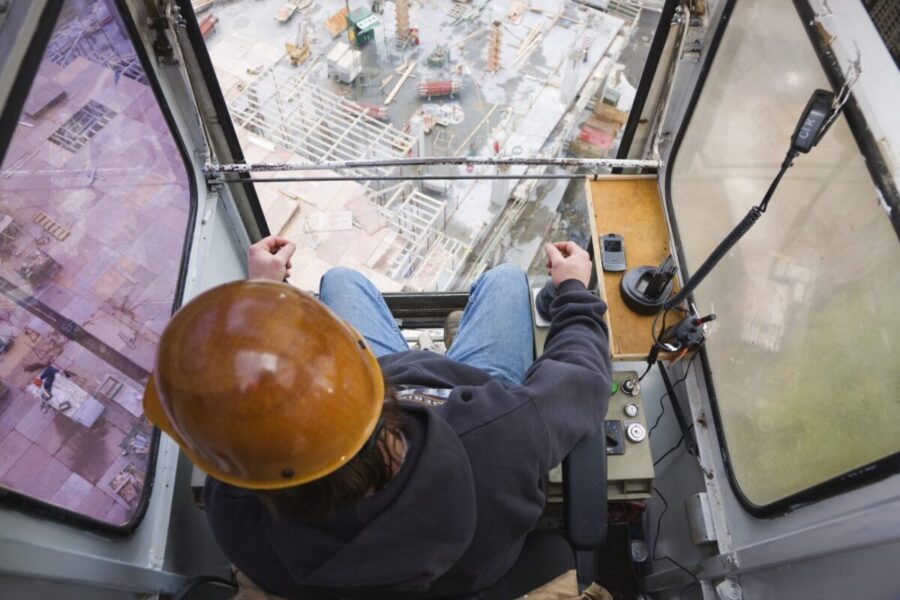 Worker Operating Crane At Construction Site