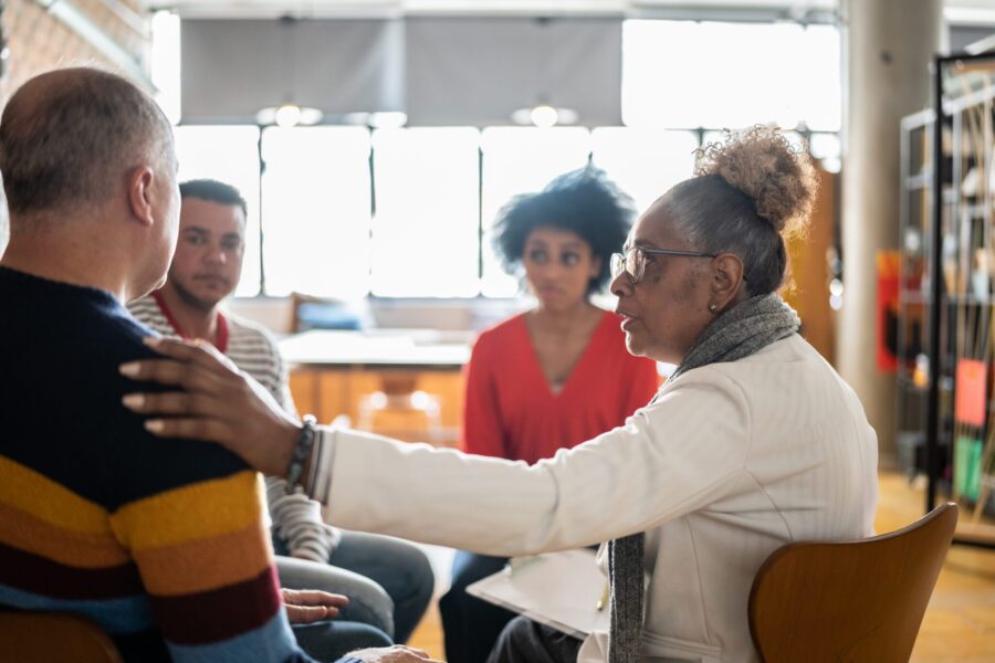 Senior woman comforting a mature man in group therapy at a coworking