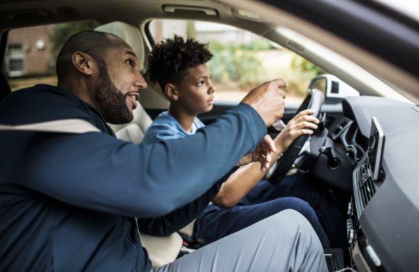 Father teaching teenage son to drive in his first car