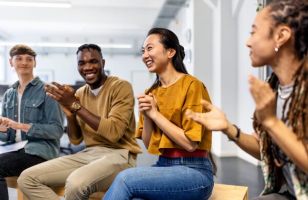 Multiracial business team applauding after a successful staff meeting. Group of business people sitting in a circle clapping hands in meeting.