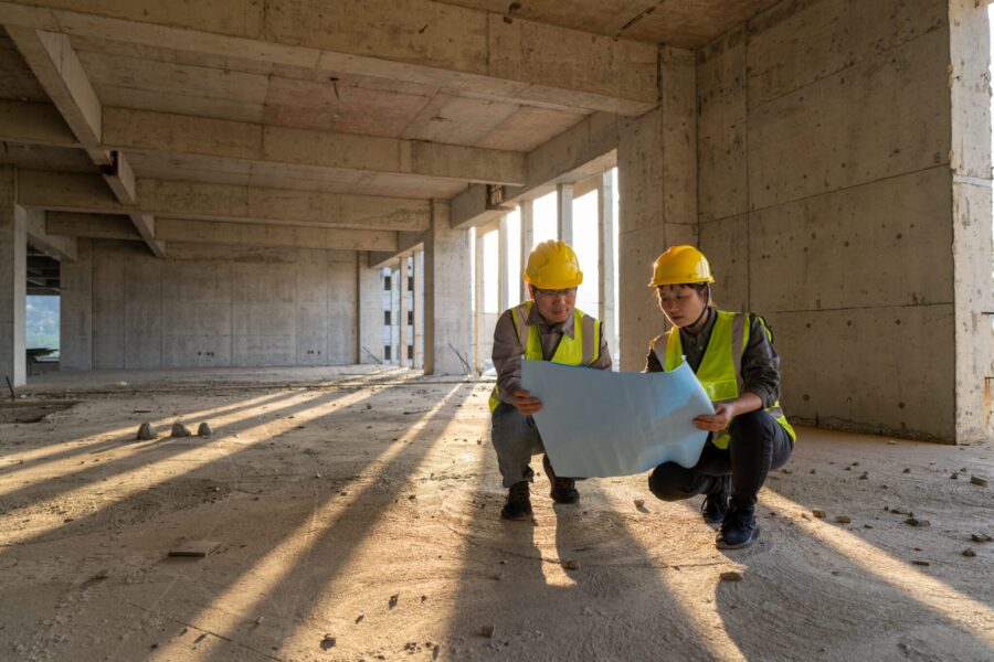 Male and female construction engineers with drawings comparing data
