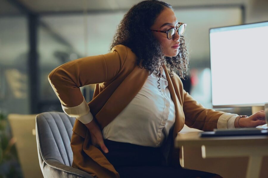 Backache, business woman and computer research at night in office with burnout, stress and spine, discomfort and mockup. Back pain, black woman and posture problem while working late on deadline