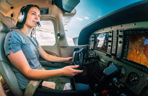 Wide Angle Shot of a Cheerful Young Adult Female Pilot Flight Instructor Flying a Small Single Engine Airplane