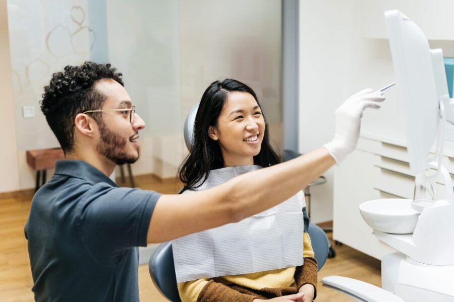 A young patient looking at a monitor and talking to her dentist about her dental health during a check up at his clinic.