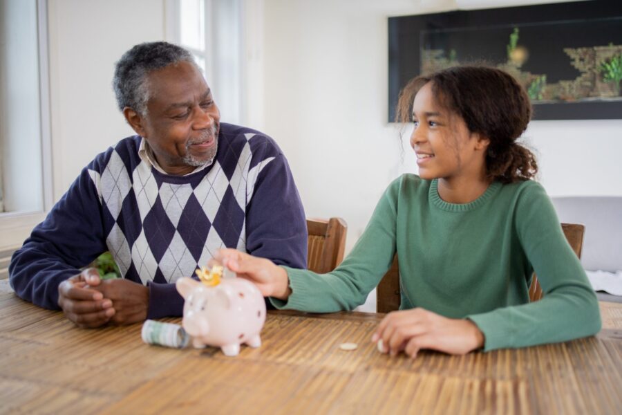 Granddaughter and grandfather save money in a piggy bank