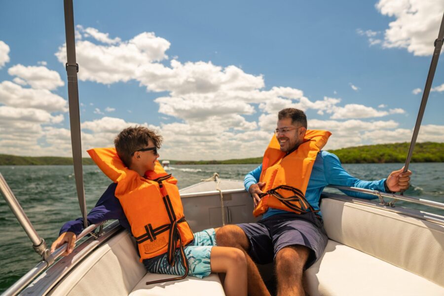 Father and son in lifejackets enjoying speedboat ride