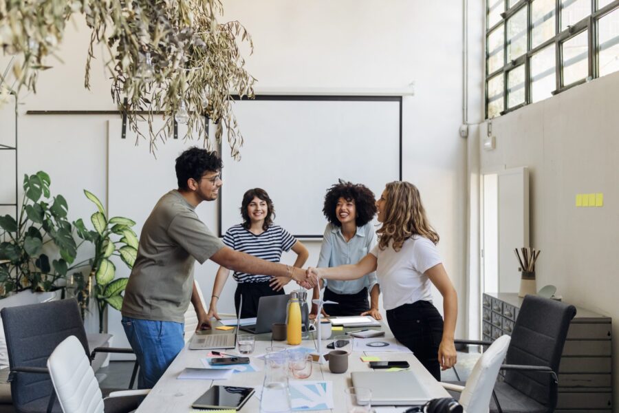 Coworkers shaking hands after business meeting in office