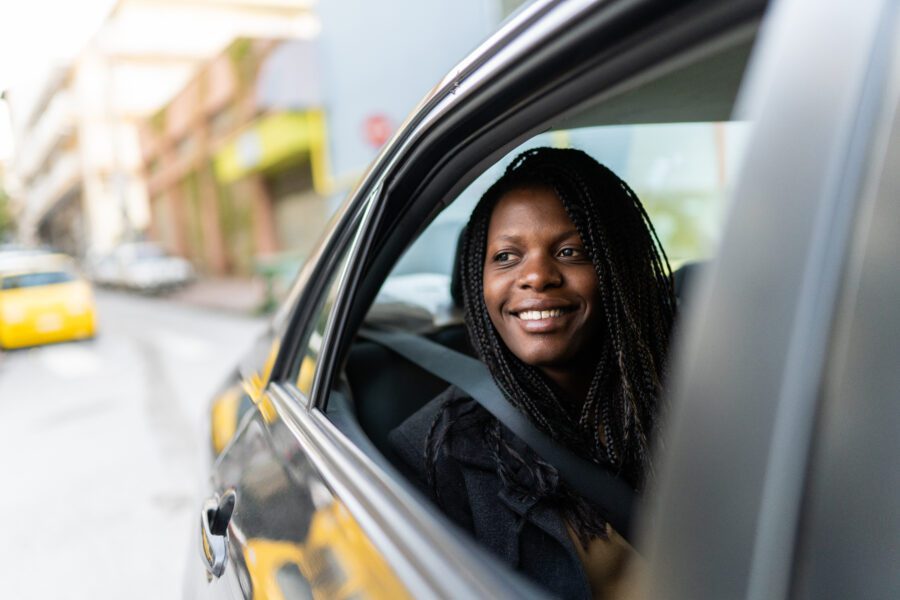 Young woman sitting in car and looking through window from back seat