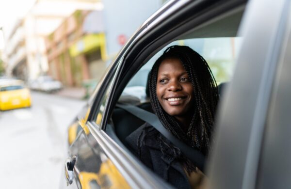 Young woman sitting in car and looking through window from back seat