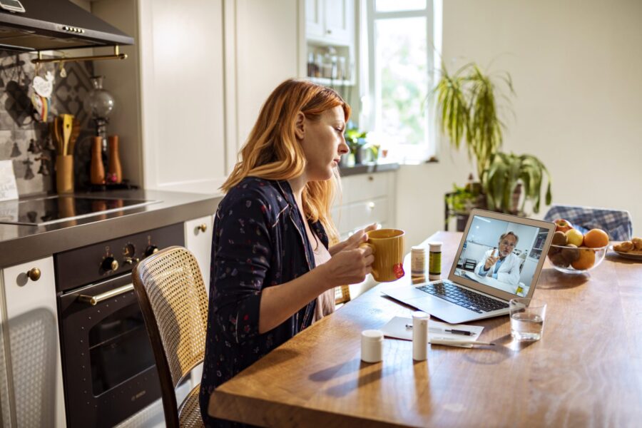 Close up of a young woman using a laptop to talk to her doctor