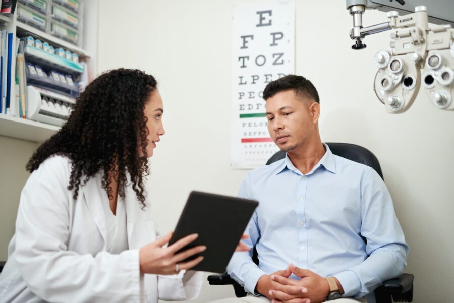 Optometry, tablet and optician with man for results, communication and consulting about vision. Healthcare, medical and ophthalmologist talking to a patient about eye care after an exam with tech