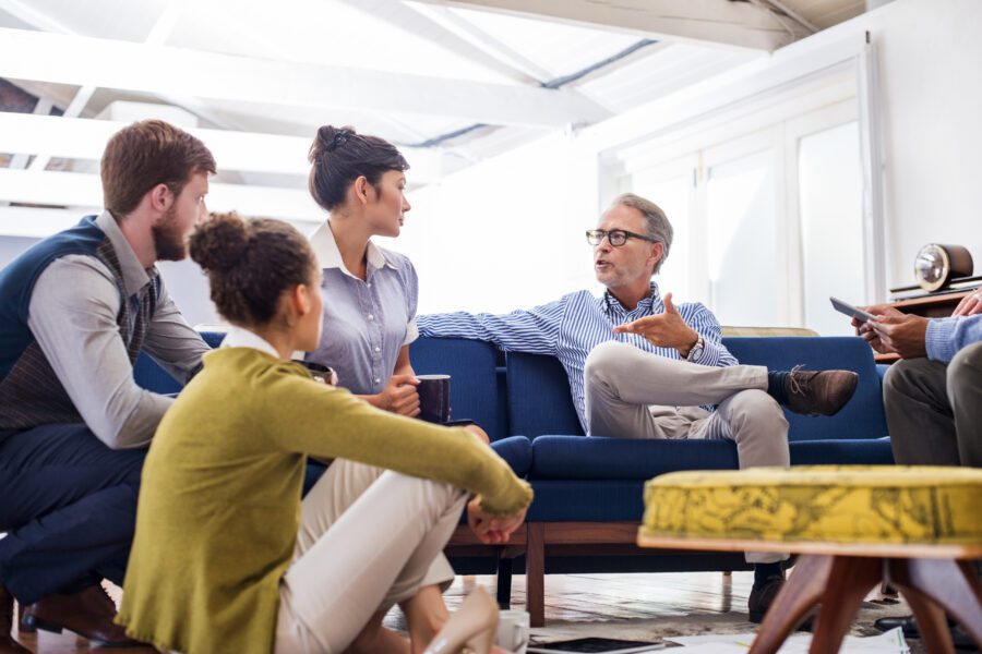 Mature businessman discussing with young colleagues in creative office