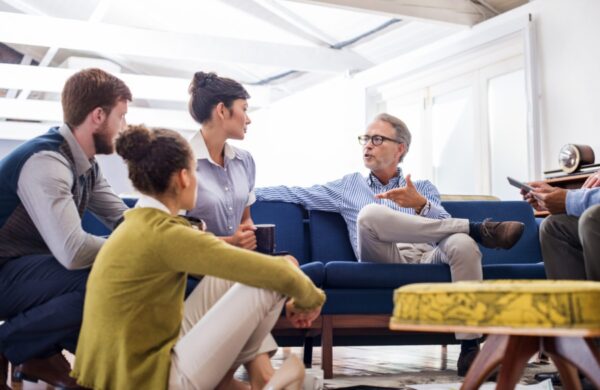 Mature businessman discussing with young colleagues in creative office