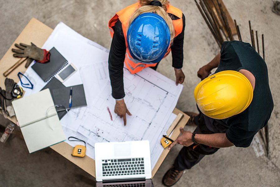Engineers and contractors on a construction job site reviewing blue prints