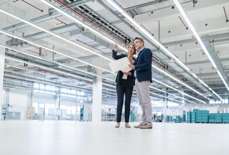 Businessman and businesswoman discussing plan in a factory hall