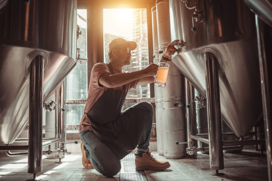 Male Brewer Pouring Beer From Tank Beer