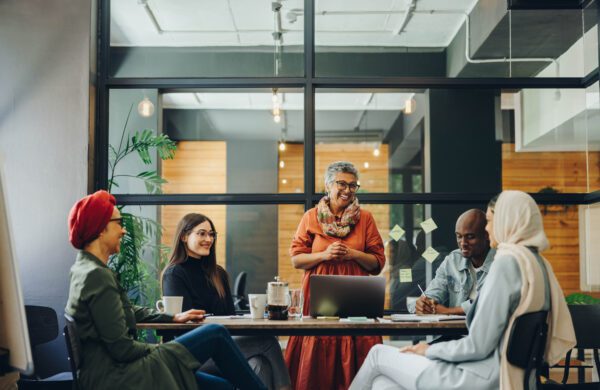 Successful businesspeople smiling happily during a meeting in a creative office. Group of cheerful business professionals working as a team in a multicultural workplace.