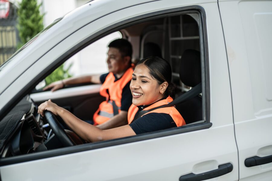 Postal workers driving a van truck to deliver packages