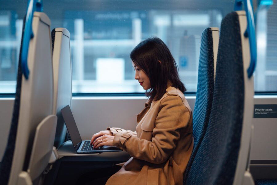 Young woman using laptop on public transport. Business travel. Business and technology concept.