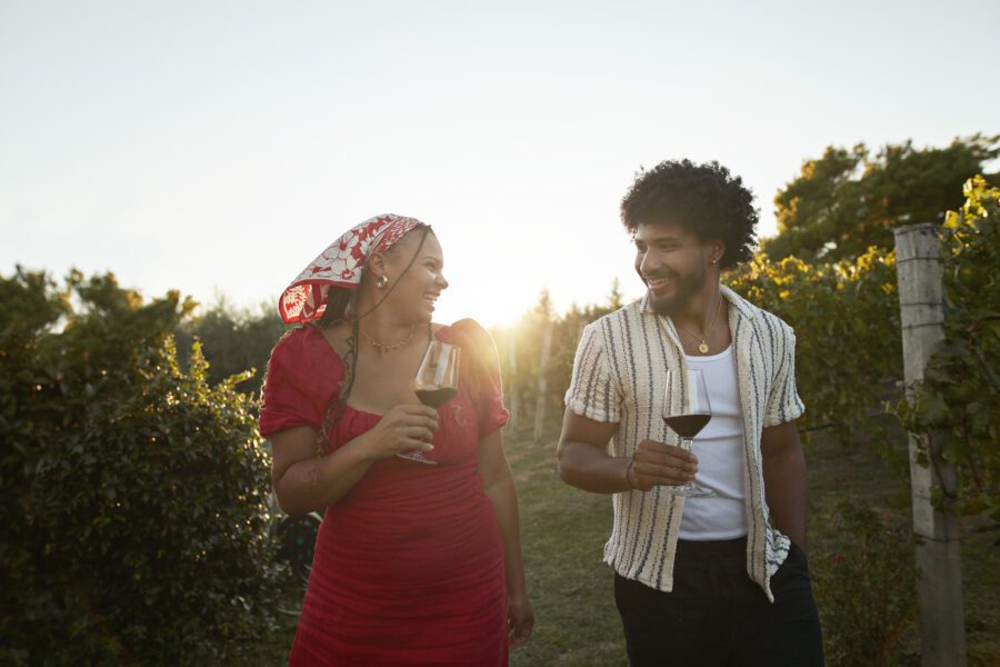 Smiling Couple With Red Wine Walking Amidst Plants