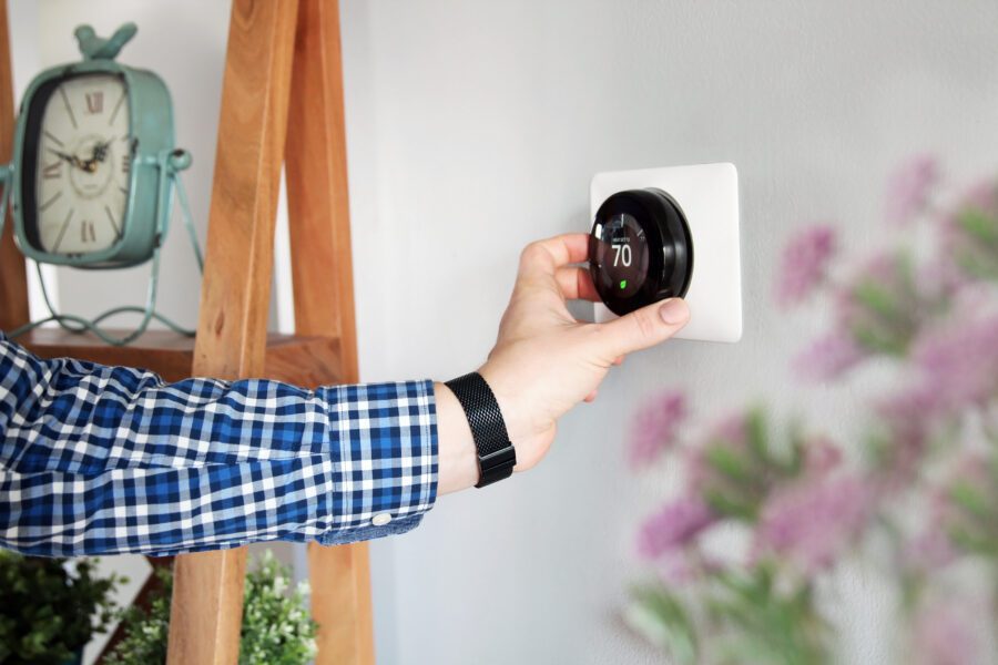 Man is Adjusting a temperature on the thermostat in the living room.