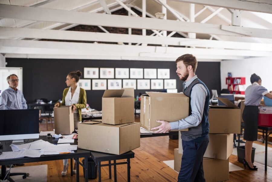 Group of business people packing cardboard boxes in creative office