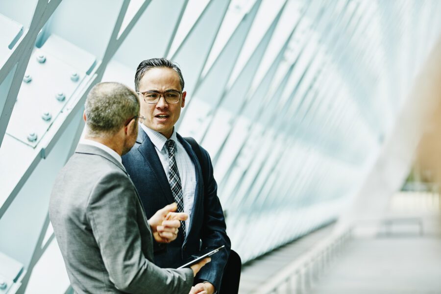 Two Businessmen Discussing Data On Digital Tablet