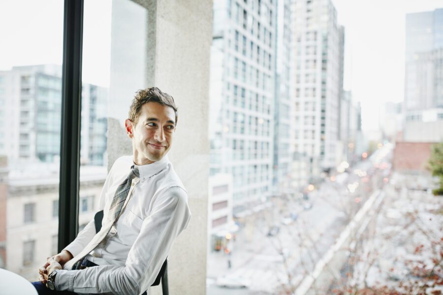 Businessman Seated In Office With View Of City