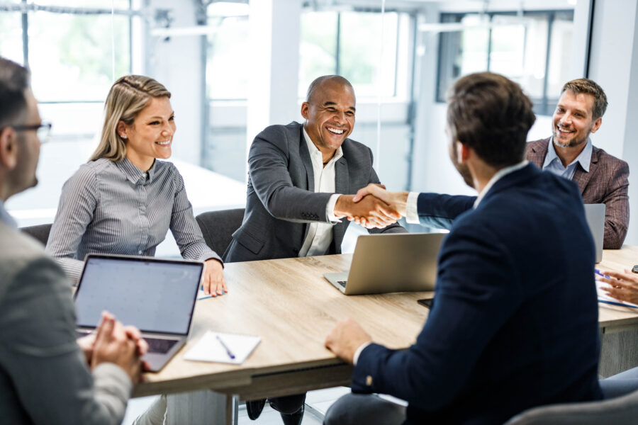 Happy male entrepreneurs came to an agreement during a meeting with their colleagues in the office. Focus is on black man.