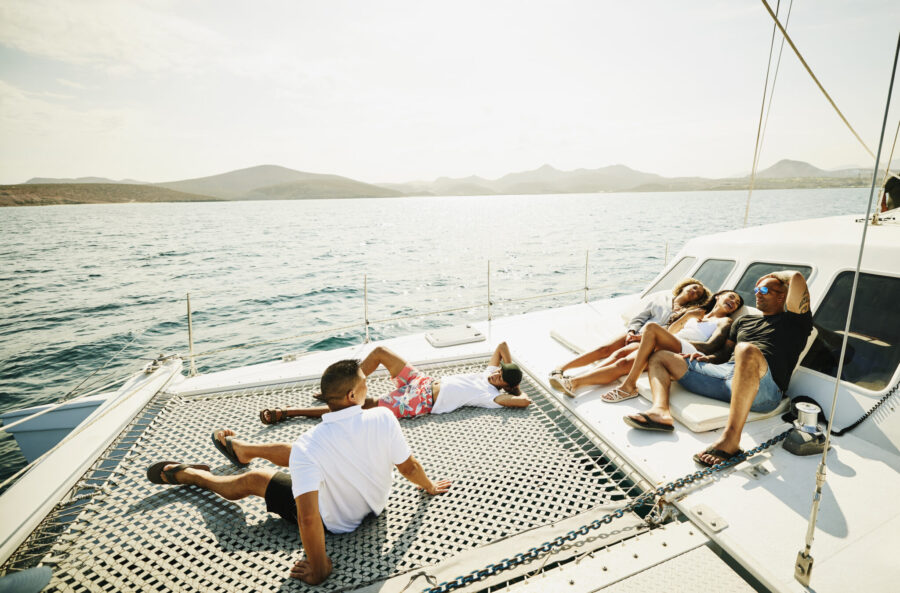 Wide Shot Of Families Relaxing On Deck Of Sailboat While On Vacation