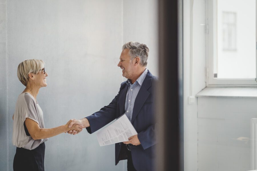 Mature Businessman And Businesswoman Shaking Hands In New Office