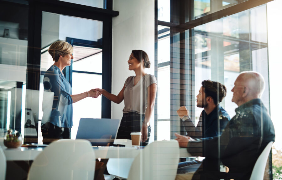 Shot of two businesswomen shaking hands together during a boardroom meeting at work