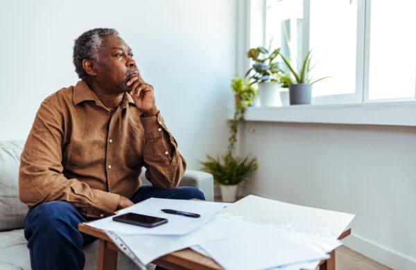 Depressed Senior Adult Man With Stacks of Papers and Envelopes