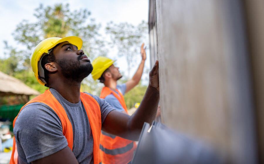 Team of construction workers installing panels while building a manufactured house - construction industry concepts