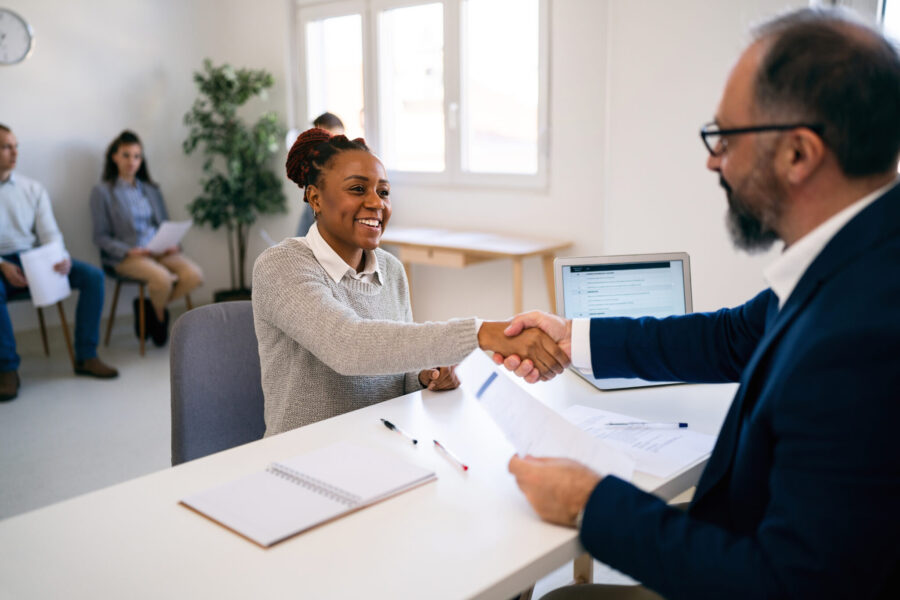 Caucasian male recruiter, handshake with a female candidate of Black ethnicity during a job interview in the office.