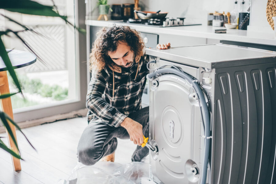 Man in a Kitchen Repairing a Washing Machine.