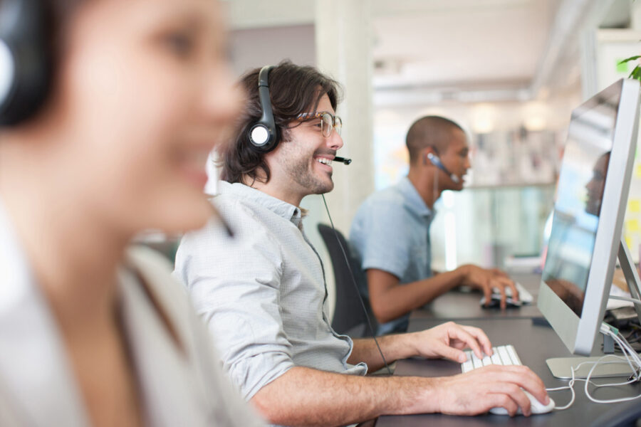 Business People With Headsets Working At Computers In Office