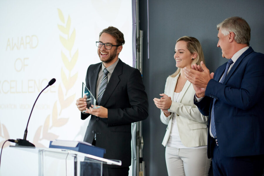 Shot of a young businessman being awarded a prize during an awards giving ceremony at a conference